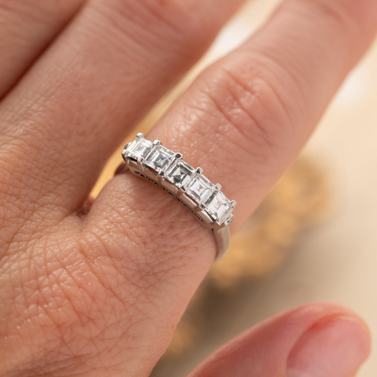 A Vintage Carré Cut Diamond Band - 4.5mm platinum ring set with five carre-cut diamonds on a finger.