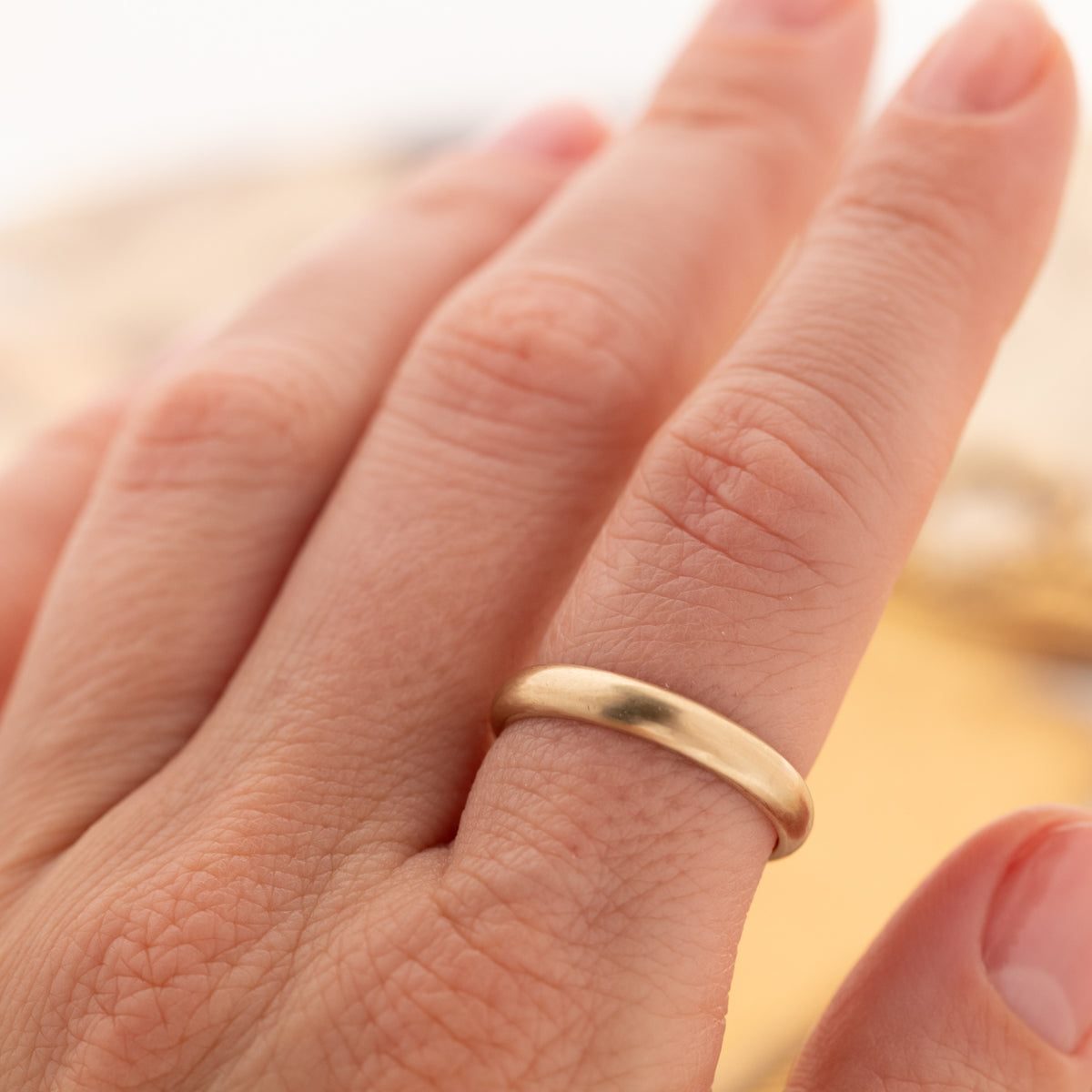 A Vintage Rounded Band, a simple 14k gold band with a vintage patina worn on a finger.