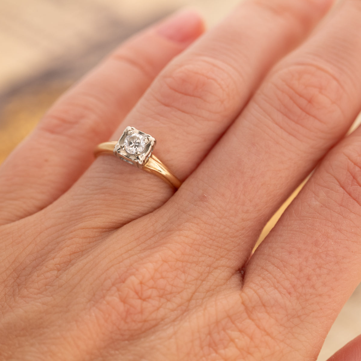 A Vintage Two Tone Diamond Ring featuring a 14k gold square-set diamond on a finger.