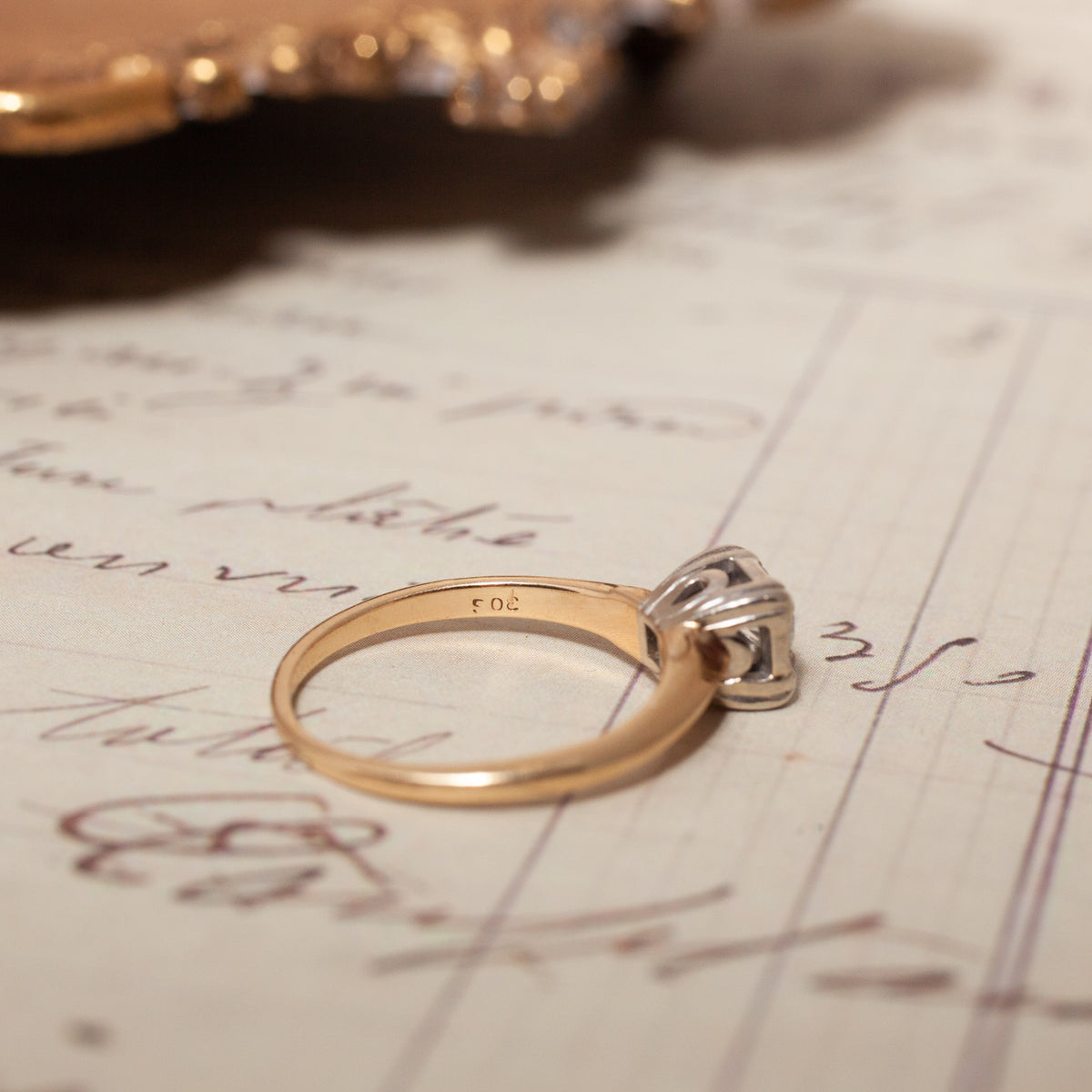 A Vintage Two Tone Diamond Ring resting on a piece of vintage handwriting.
