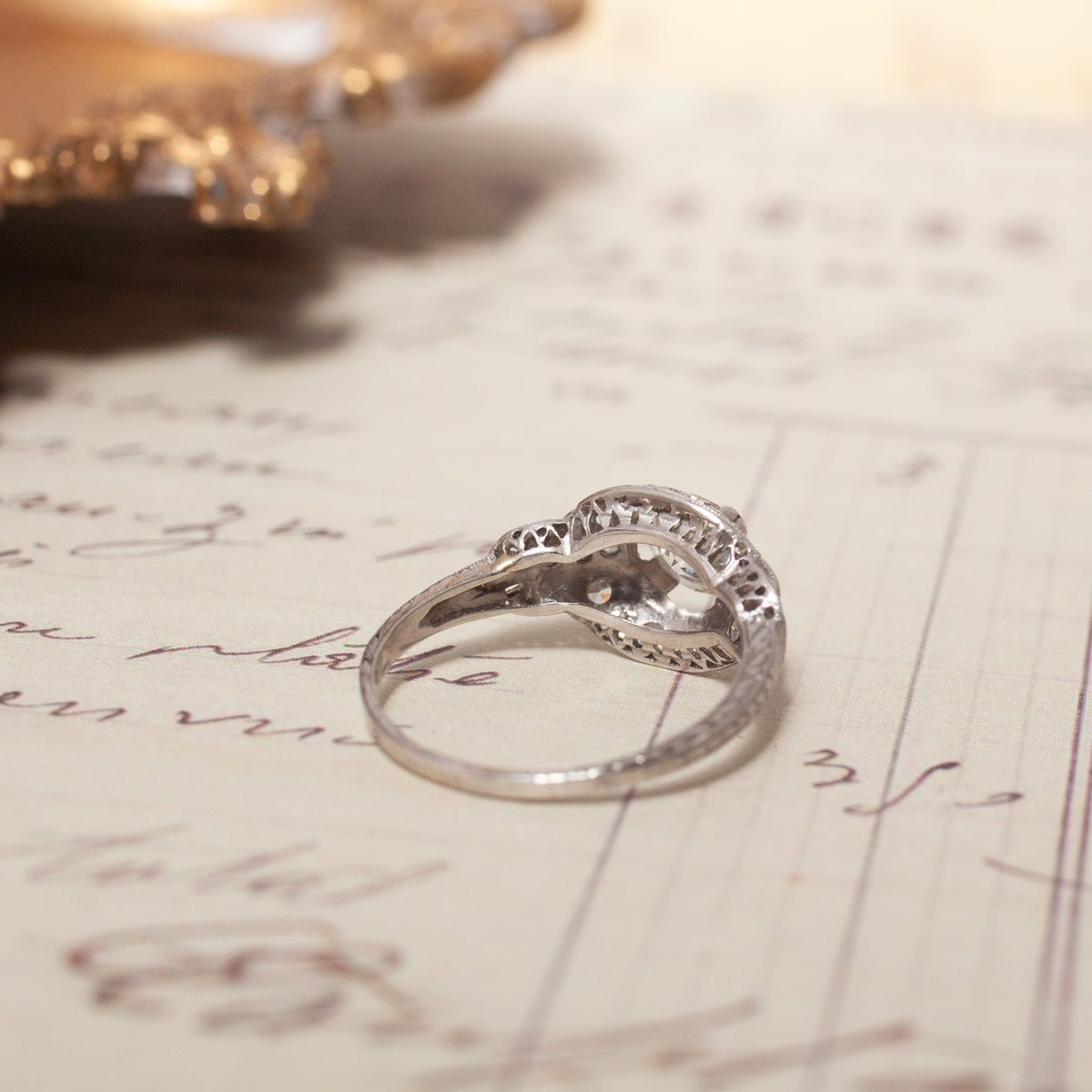 A Vintage Transitional Cut Diamond Halo Ring with a central setting resting on an antique document.