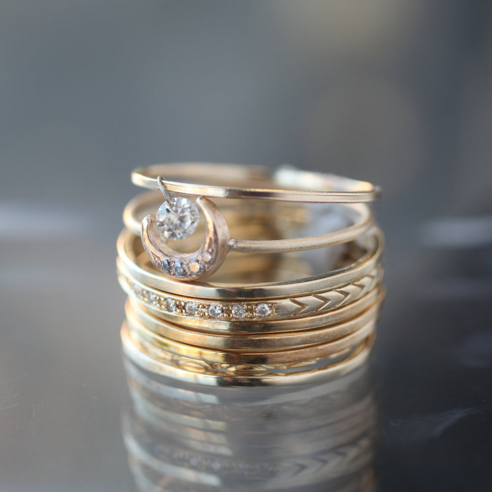 Five full cut rings stacked in between four yellow gold and diamond inlay stackable rings