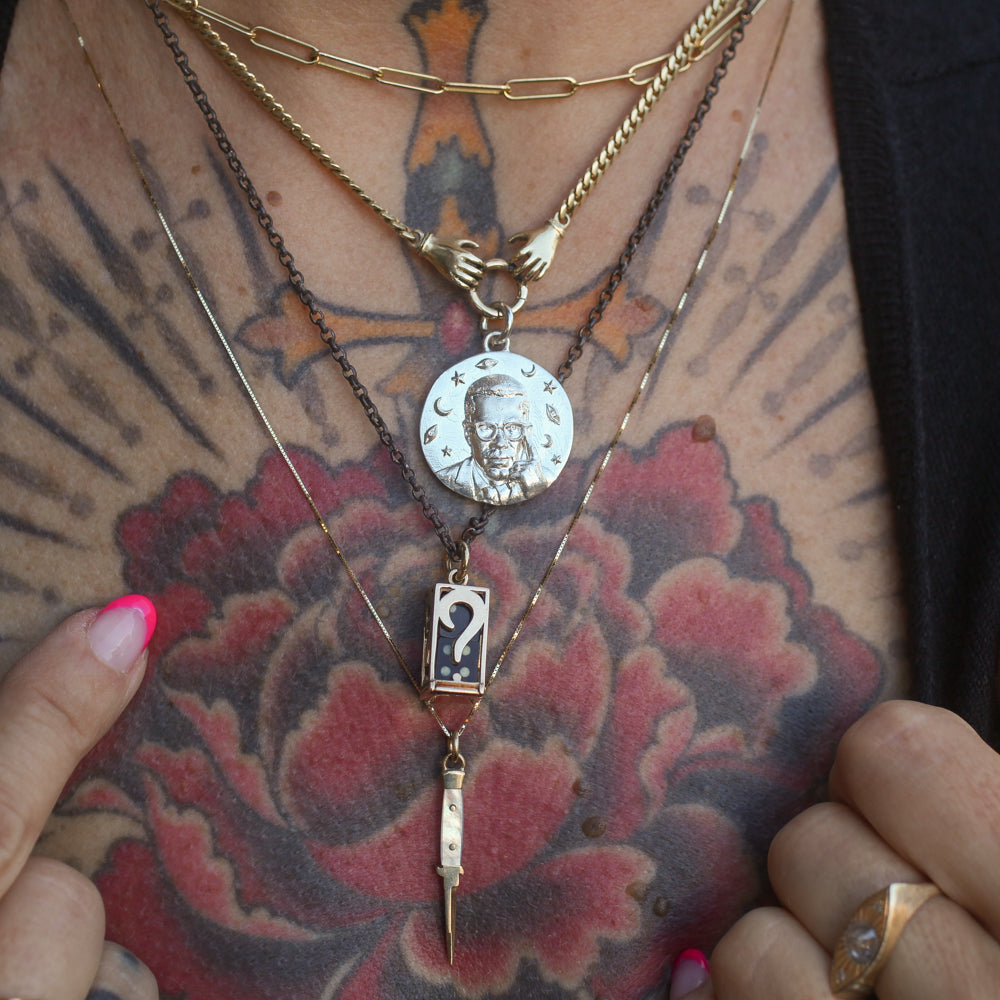 logger's necklace at the top of a four tier necklace stack of chains with variated pendant designs