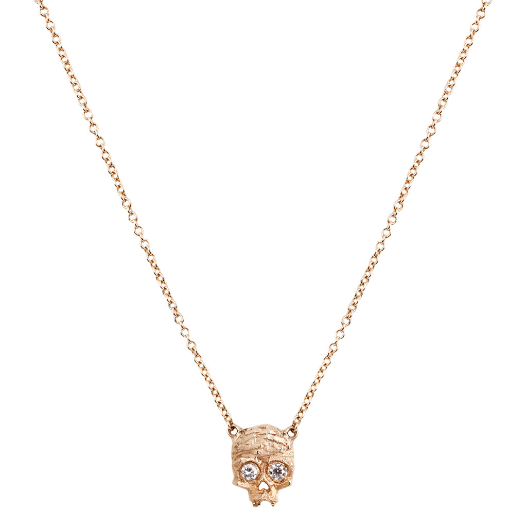 a skull necklace with two tiny diamond eyes with a cubist texture