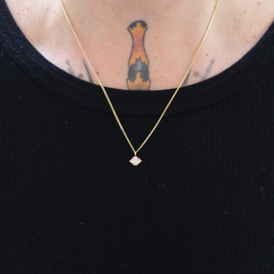 Person wearing a black top, a Fiat Lux Arcadia Necklace, and a colorful tattoo on their upper chest.